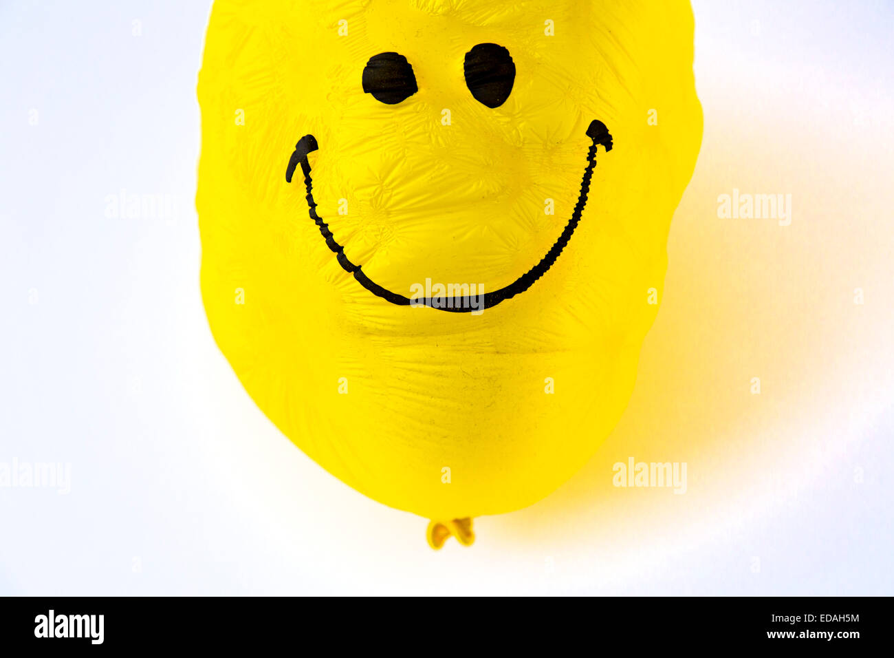 old Balloon, yellow, shriveled with friendly smiley face,  sunken, wrinkled Stock Photo