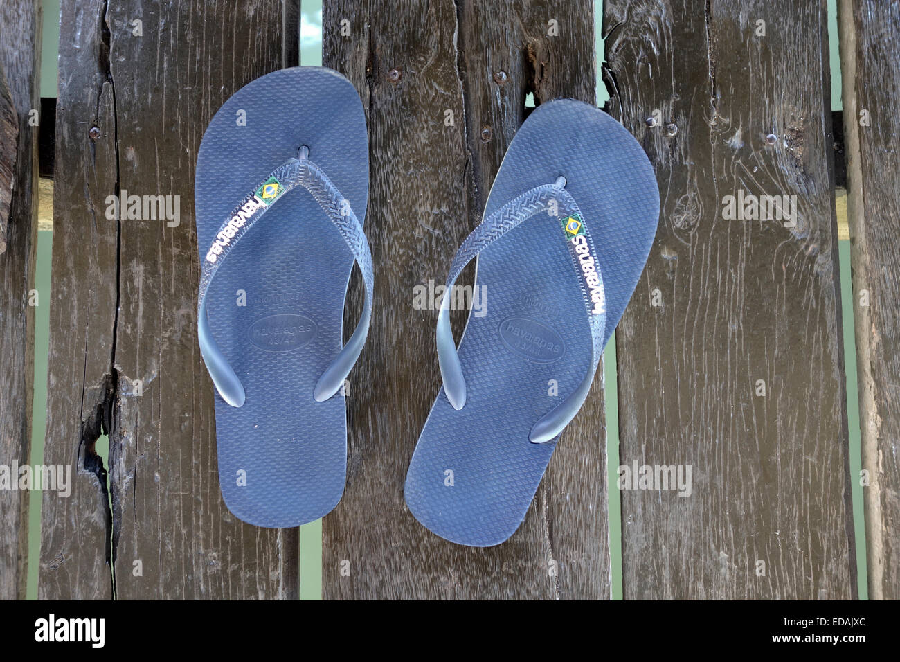 Pair of flip-flops on a wooden deck seawater underneath Stock Photo