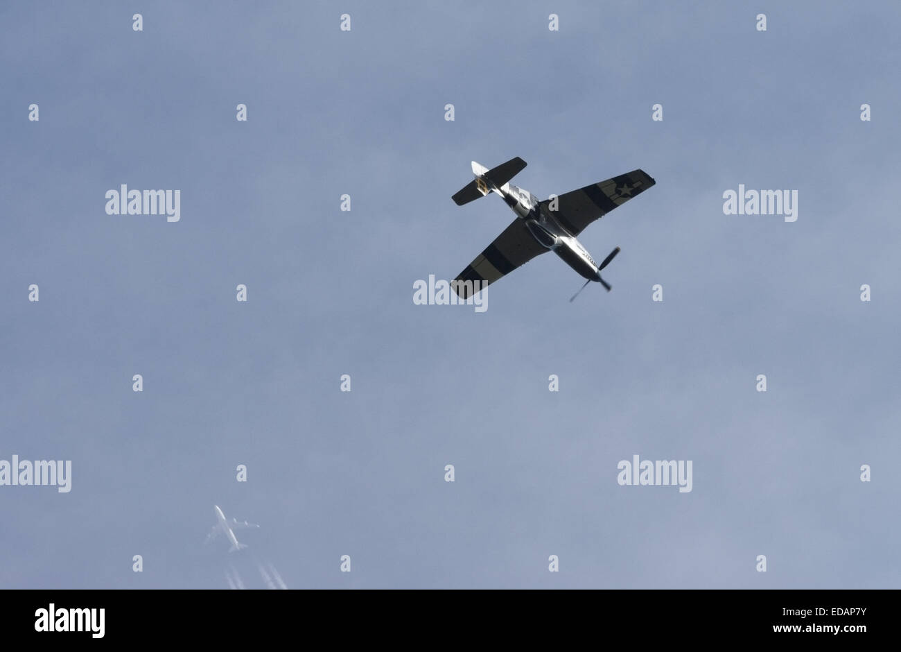 P51 Mustang at the top of a loop during a display with an airliner in the background Stock Photo
