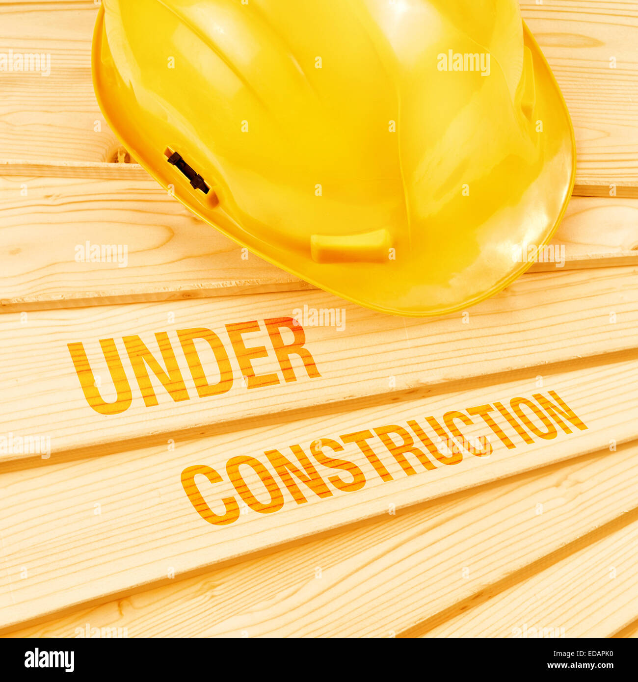 Under construction concept, Yellow hardhat on pine wood planks. Stock Photo