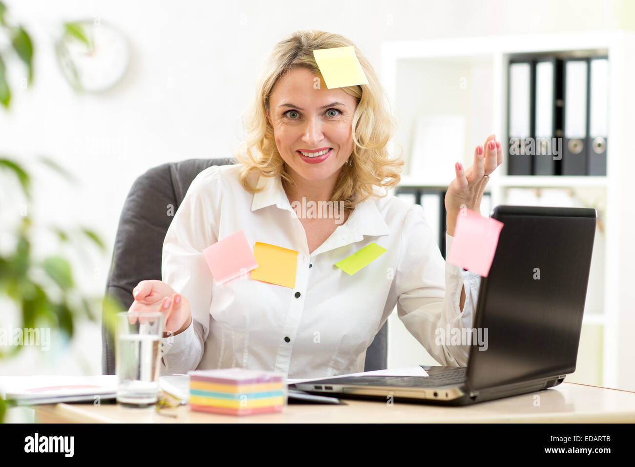 businesswoman overwhelmed with sticky reminder notes Stock Photo