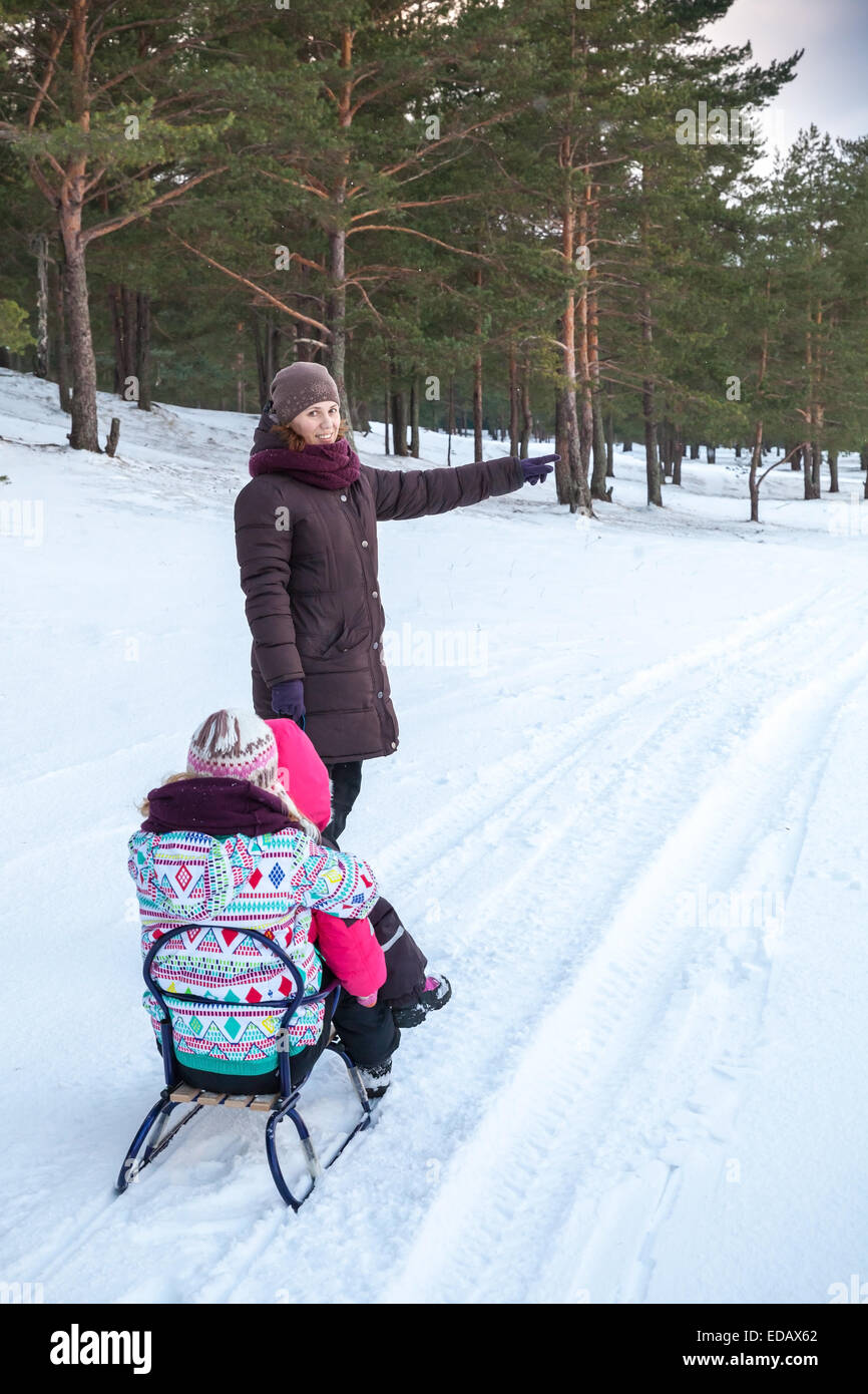 Caucasian family on the winter walking. Mother pulls sled with her two daughters Stock Photo