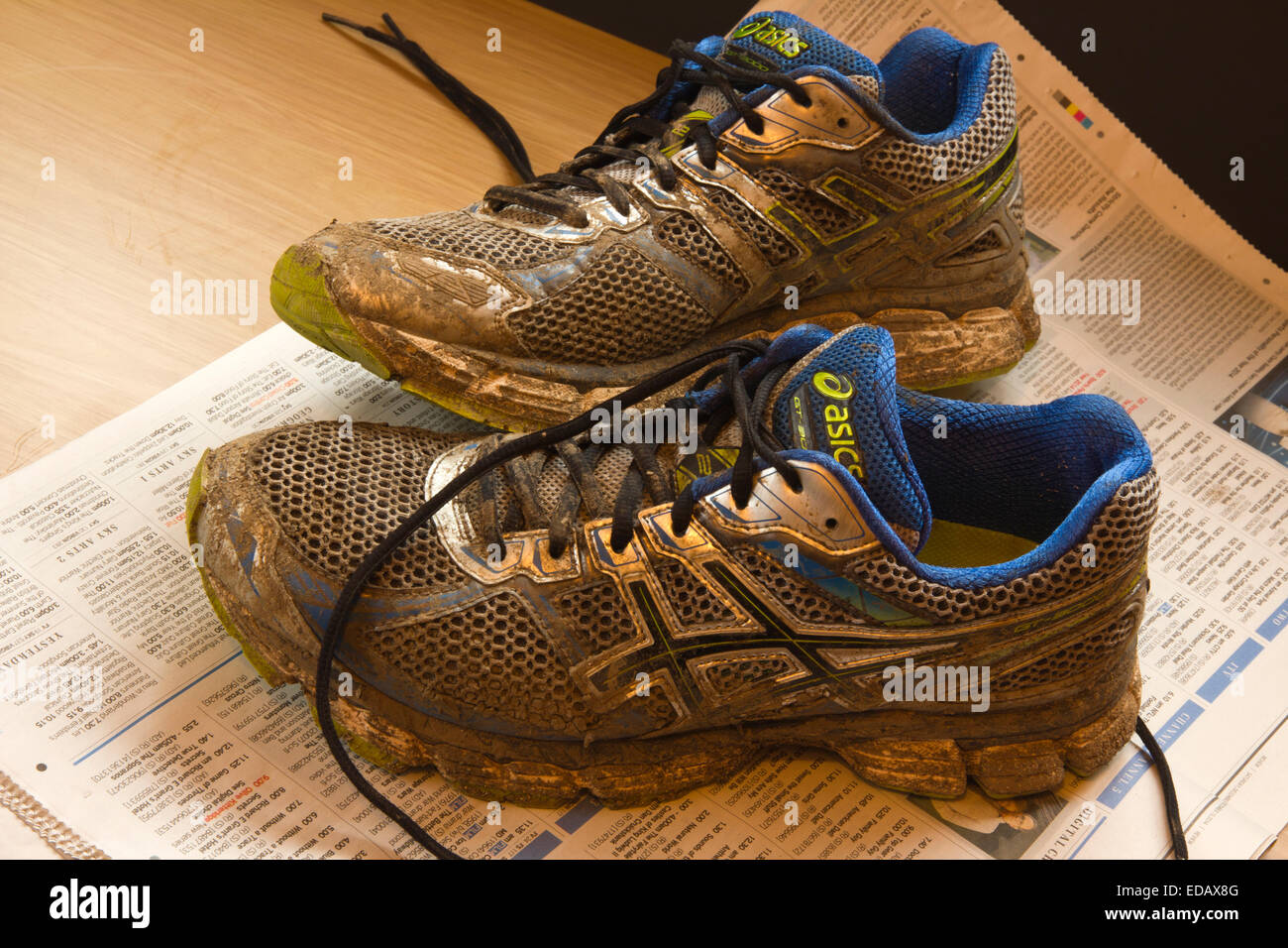 Dity Muddy Trainers on newspaper protecting the floor Stock Photo