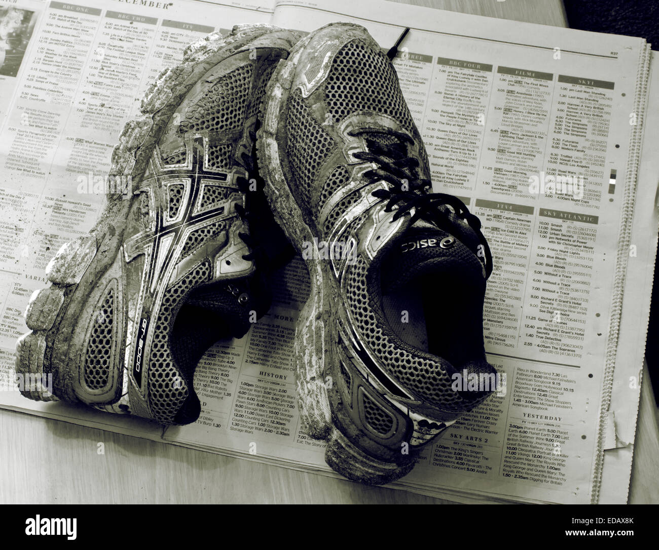 Dirty Muddy Training shoes on a newspaper protecting the floor Stock Photo
