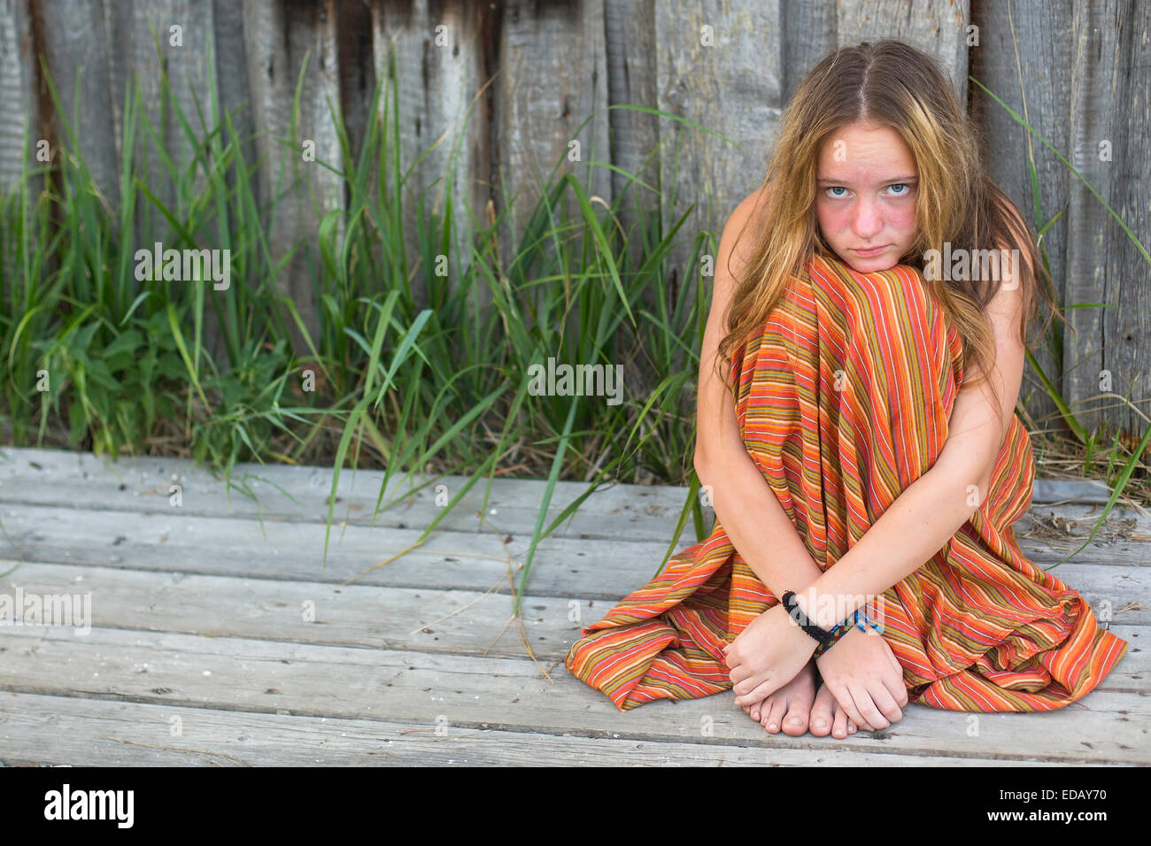 Young hippie girl sitting on the ground outdoors. Picture with space for text. Stock Photo