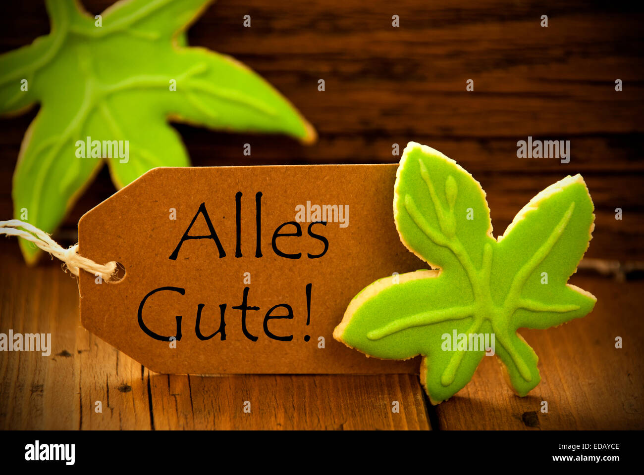 Brown Organic Label With German Text Alles Gute On Wooden Background With Two Leaf Cookies And Frame Stock Photo