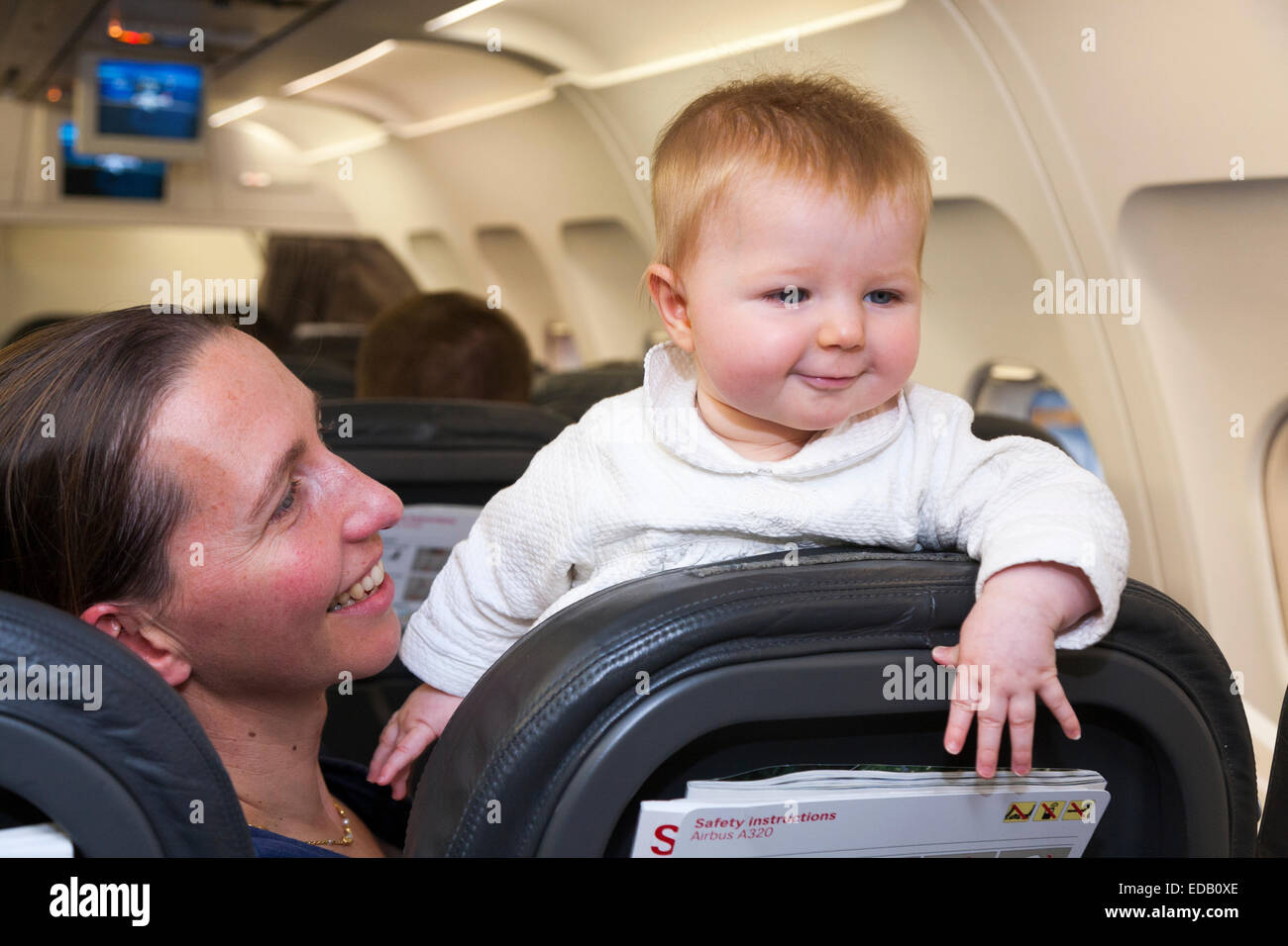 Passenger / mum / mother going on holiday / vacation with her baby travelling on an air plane / airplane / aeroplane / flight. Stock Photo