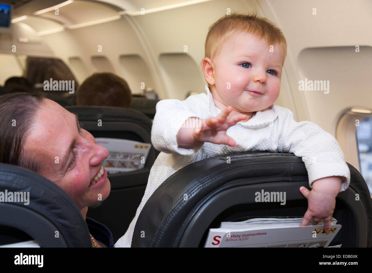 Passenger / mum / mother going on holiday / vacation with her baby travelling on an air plane / airplane / aeroplane / flight. Stock Photo
