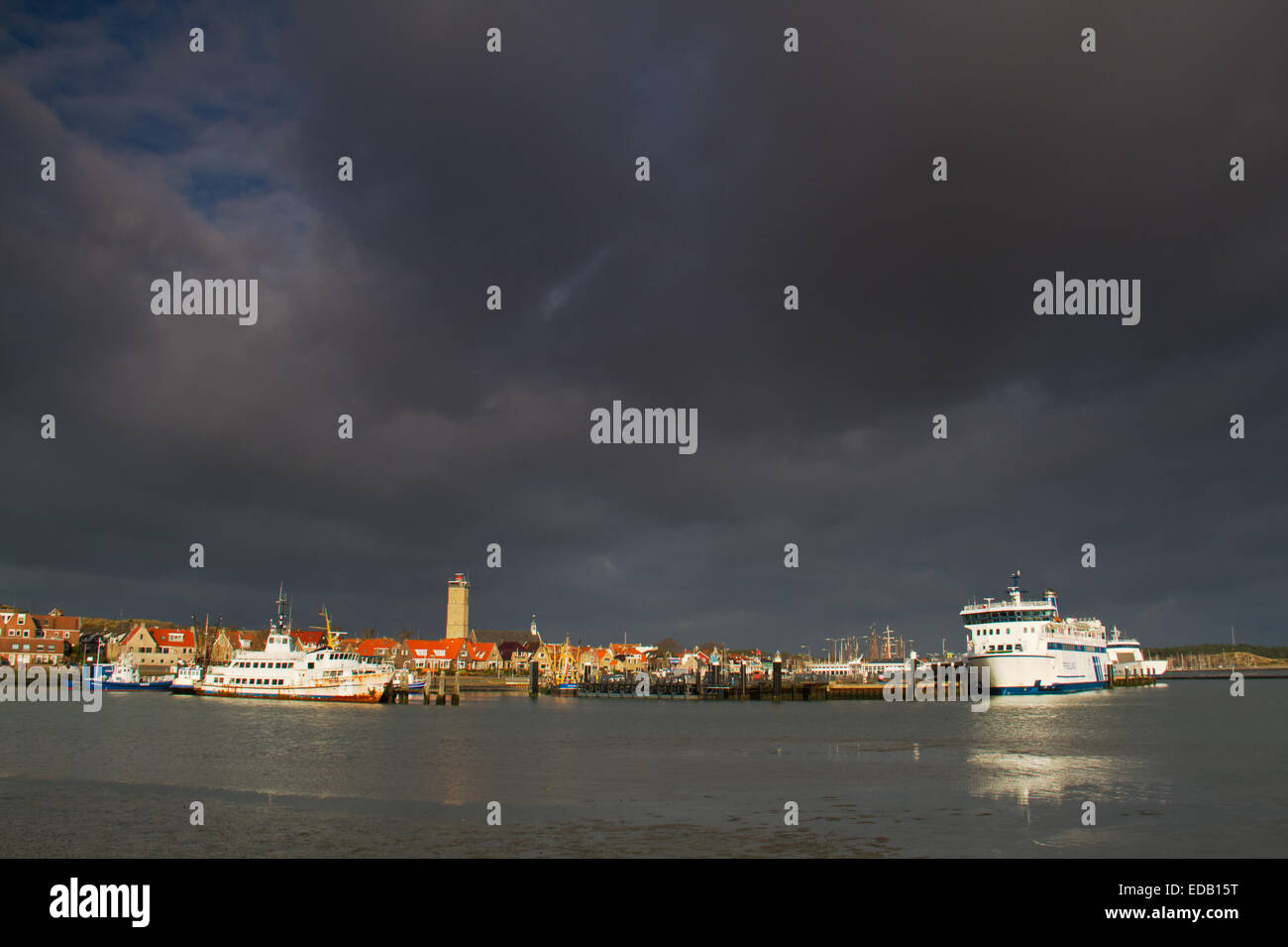 Two ferries in the harbour of the Dutch island Terschelling, in the backgroud a lighthouse Stock Photo