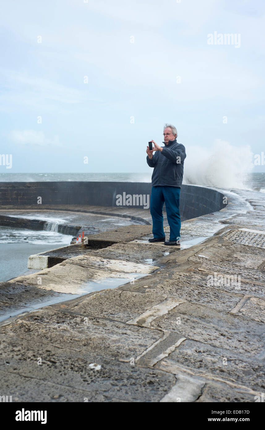 Man taking a selfie during bad weather on the Cobb in Lyme Regis, Dorset, England, UK Stock Photo