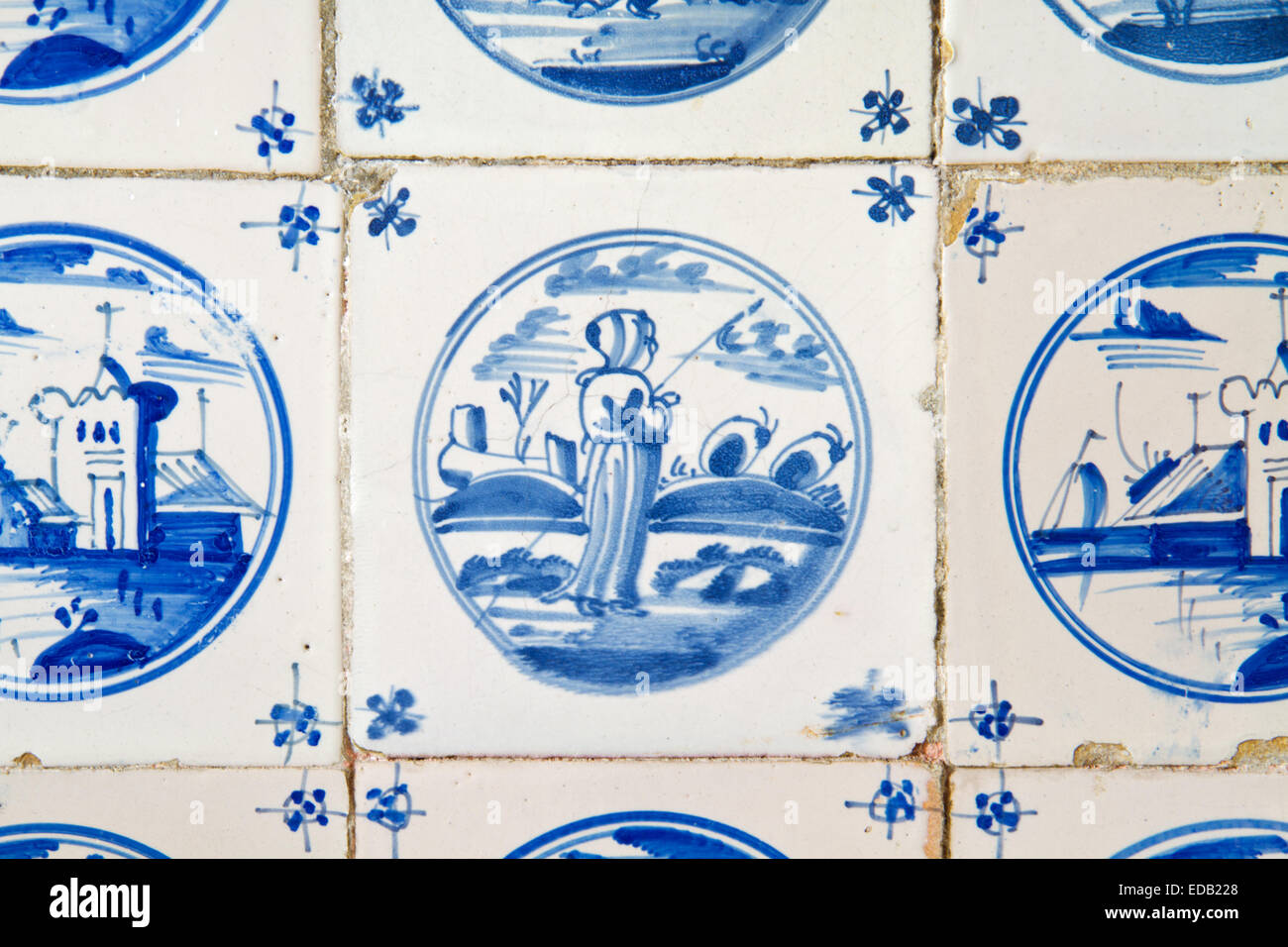 Painting of a woman in a landscape on an antique dutch tile on the kitchen wall of an old building Stock Photo