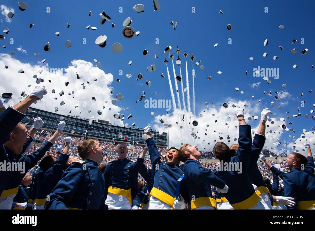 Newly commissioned second lieutenants throw their hats in the air during the commencement ceremony as the Thunderbirds fly over Falcon Stadium at the United States Air Force Academy May 28, 2014 in Colorado Springs, CO. Stock Photo