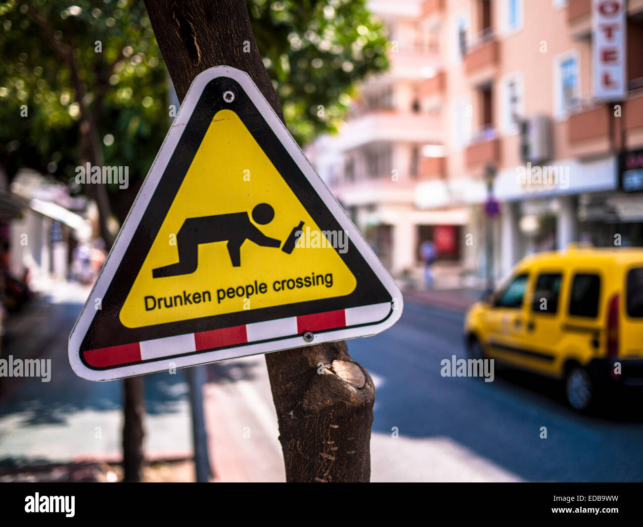 Street sign beside road in Turkish holiday resort, warning motorists of the dangers of drunken people crossing. Stock Photo