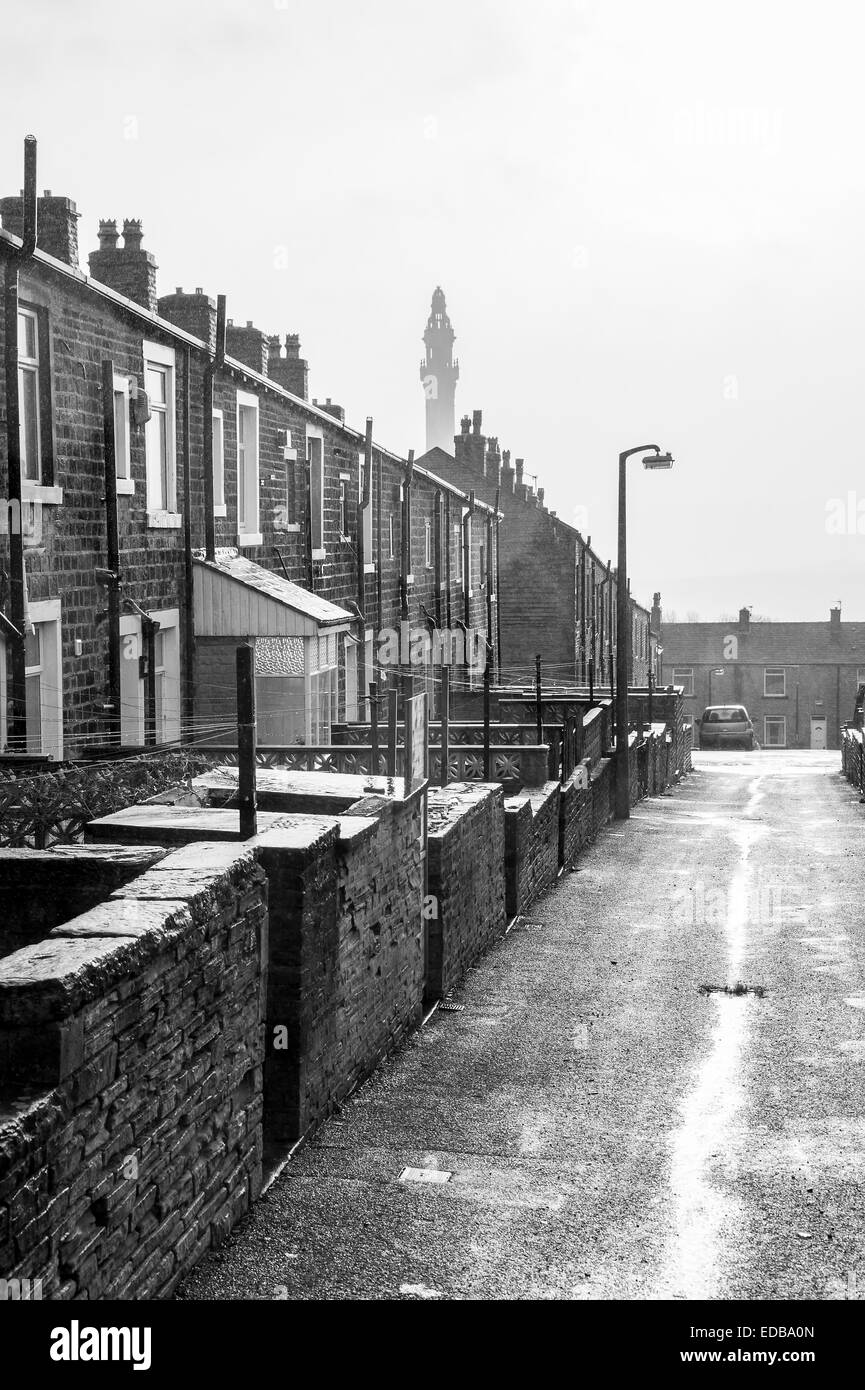 A rainy wet day in Yorkshire showing a typical Victorian terraced street leading towards a folly named Victorian Wainhouse Tower Stock Photo