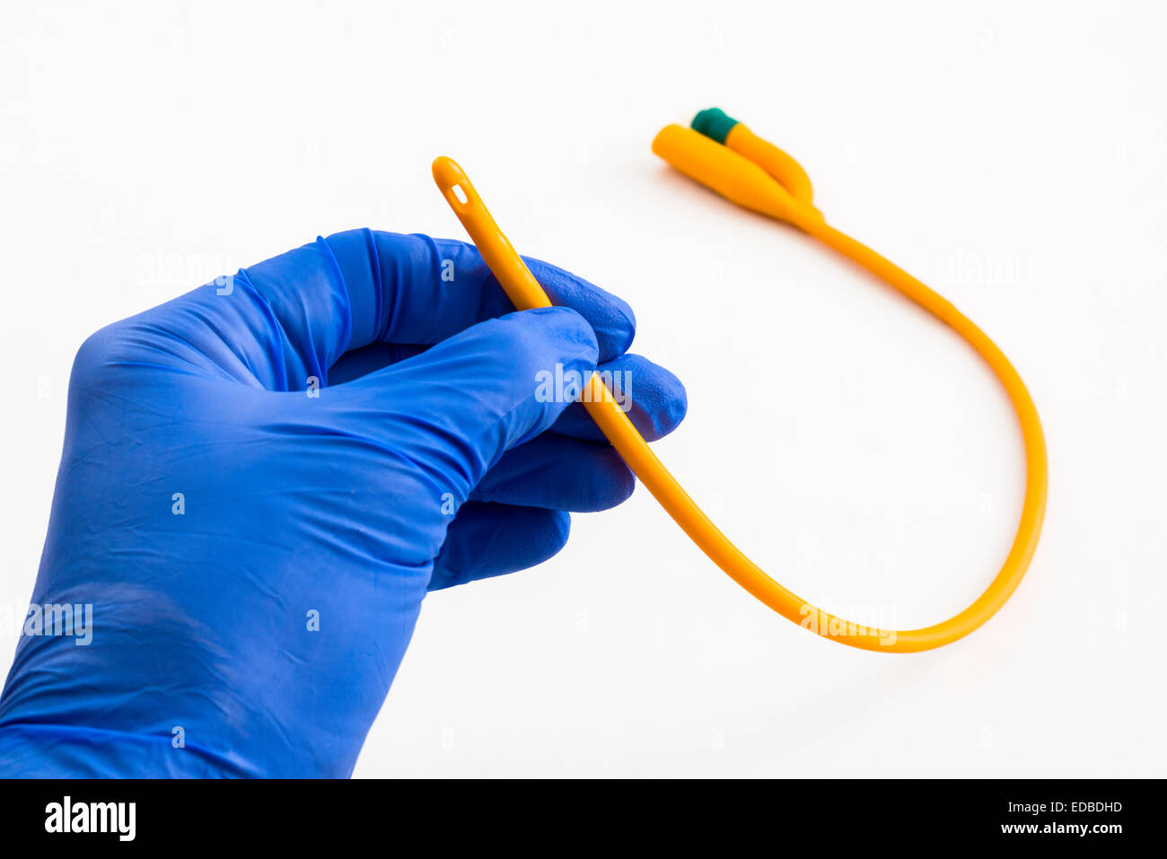 A hand with a blue medical glove is holding a balloon catheter Stock