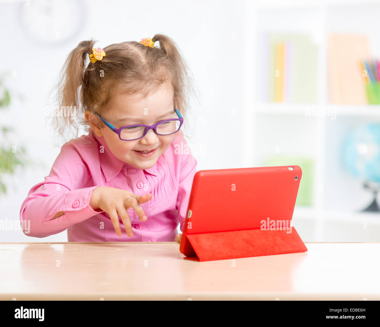 Kid with tablet PC in glasses learning with interest Stock Photo