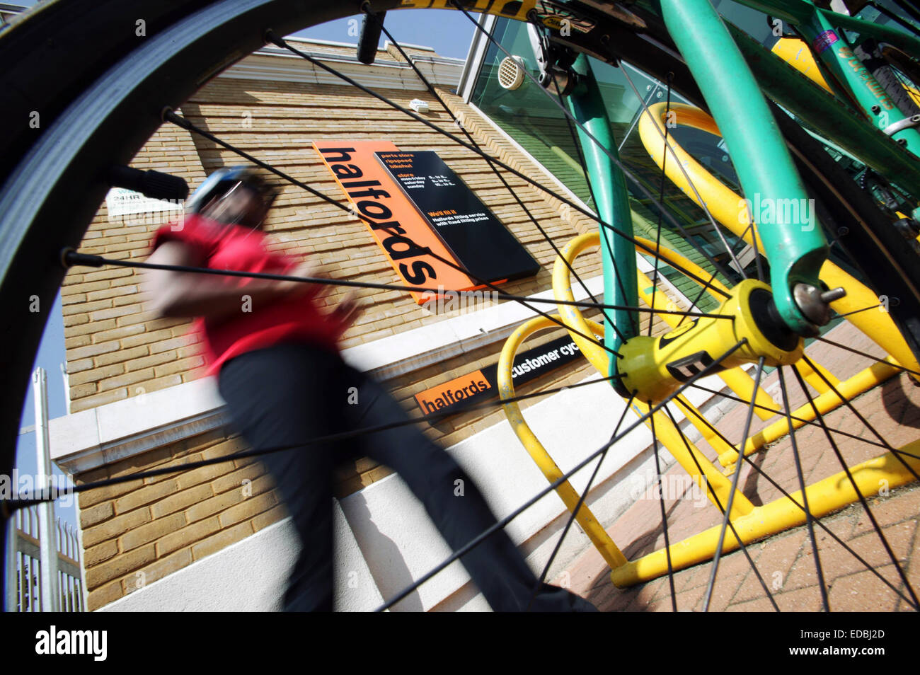 A cyclist walking to his bike outside a Halfords store. Stock Photo