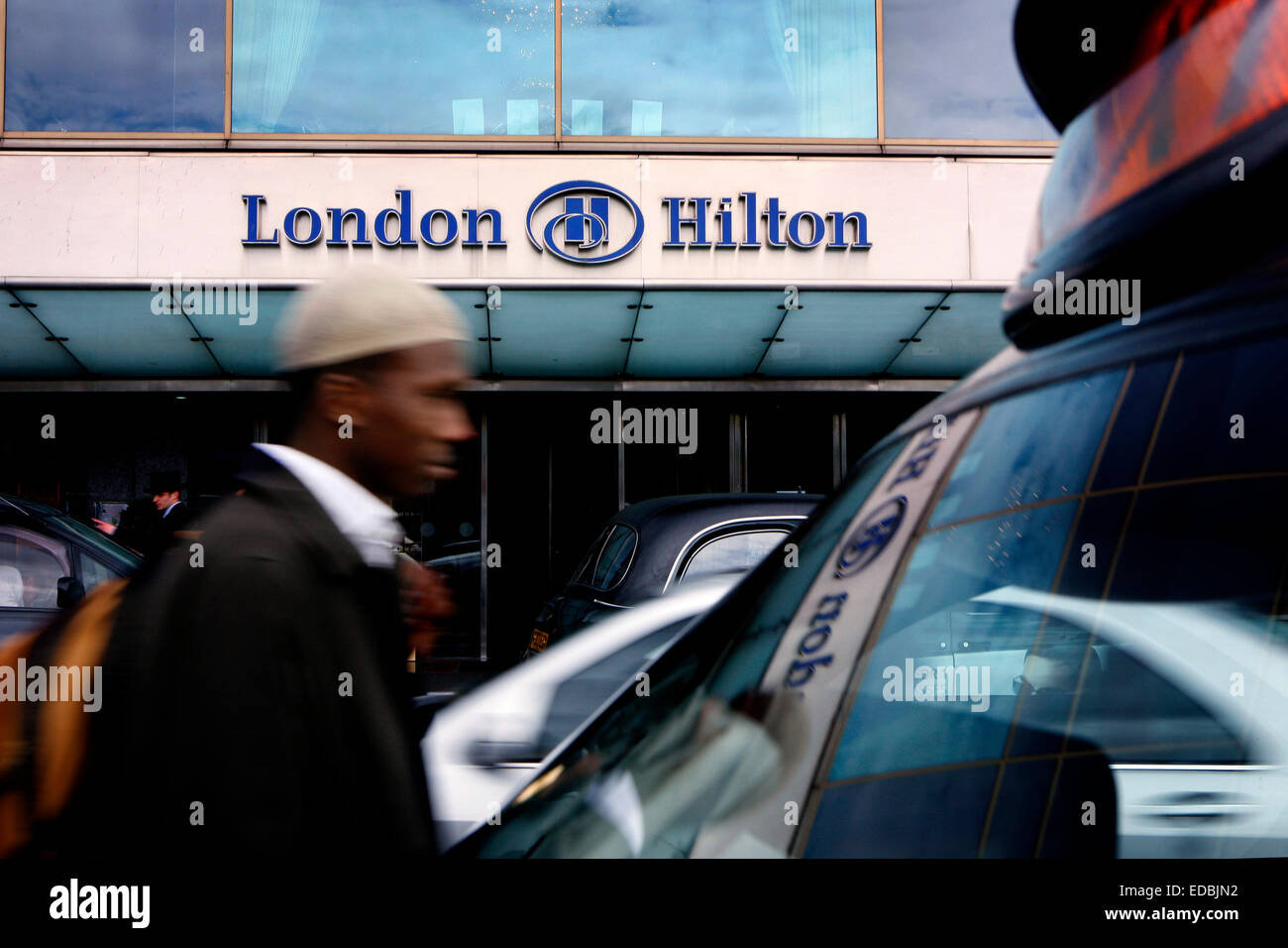 A man passing the Hilton Hotel on Park Lane, London. Stock Photo