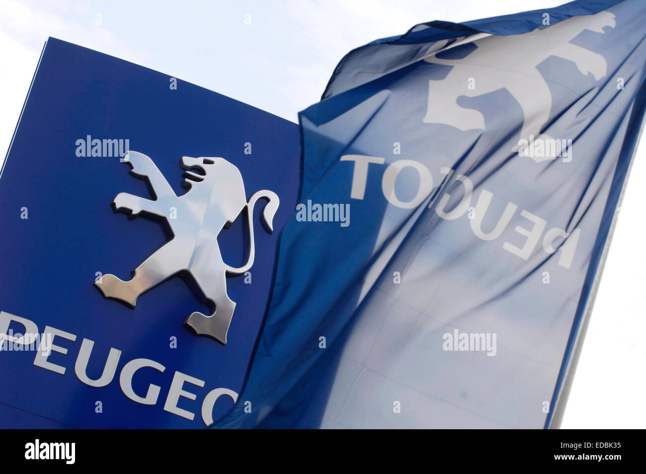 A Peugeot dealership flag and branded signage. Stock Photo