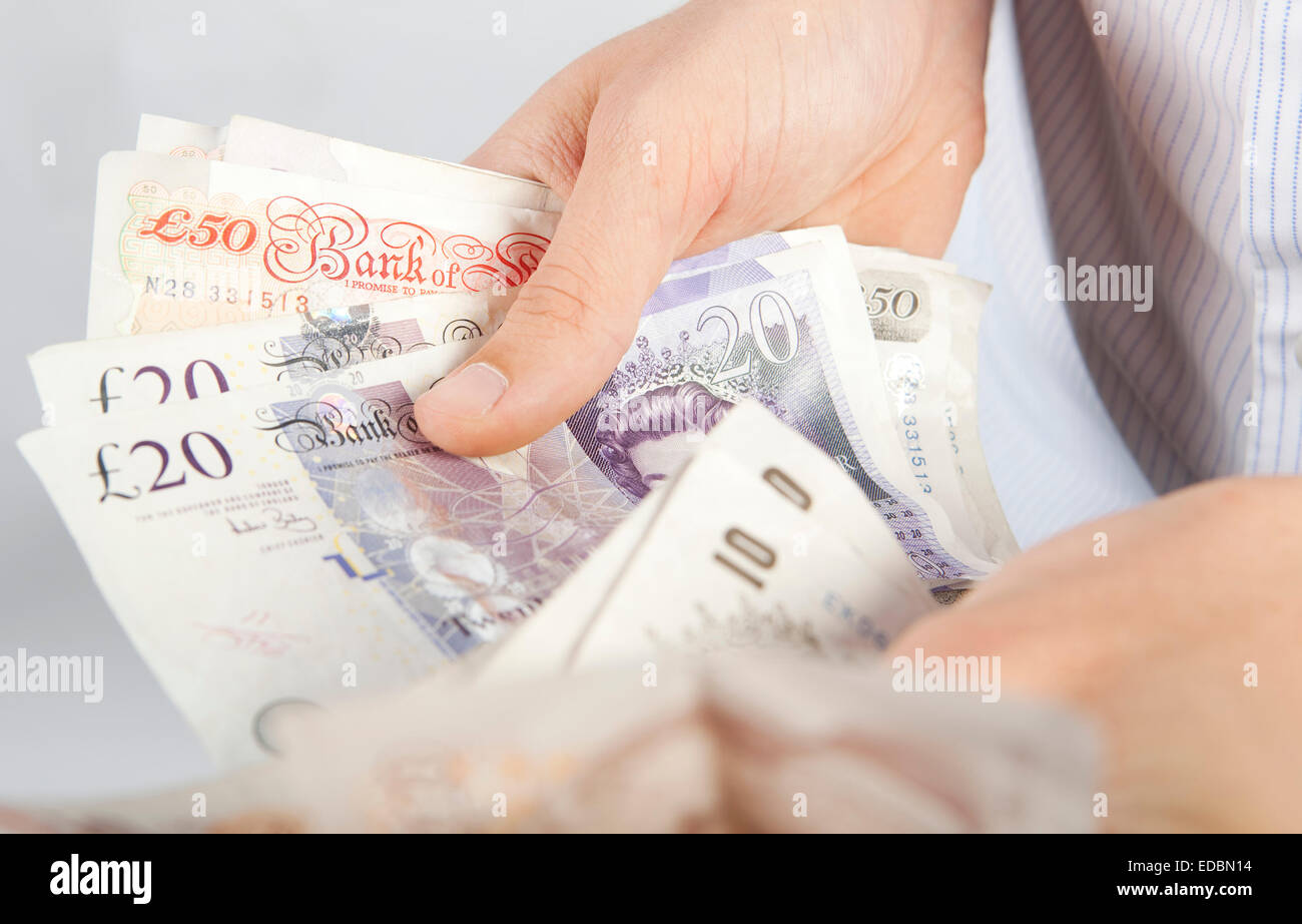 A man counting various denominations of UK pound notes. Stock Photo