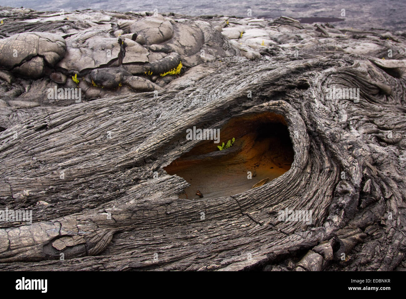 A hole in a hardened basaltic lava flow of pahoehoe type with sharp glassy edges Stock Photo