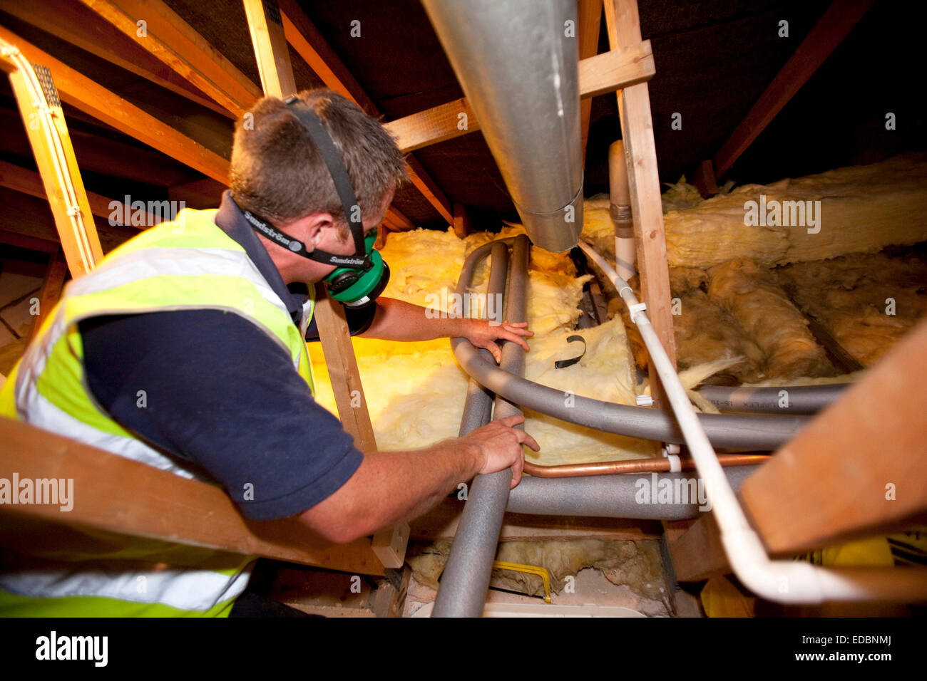 Illustrative image of loft insulation. A worker from Total Insulation Solutions lags water pipes