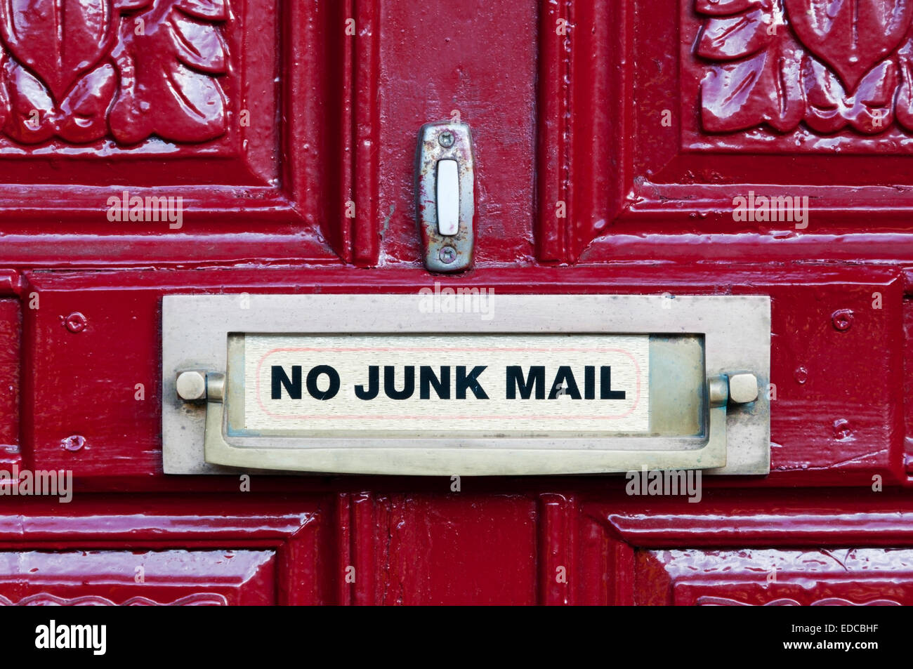 No Junk Mail sign on a bright red front door and associated door furniture. Stock Photo