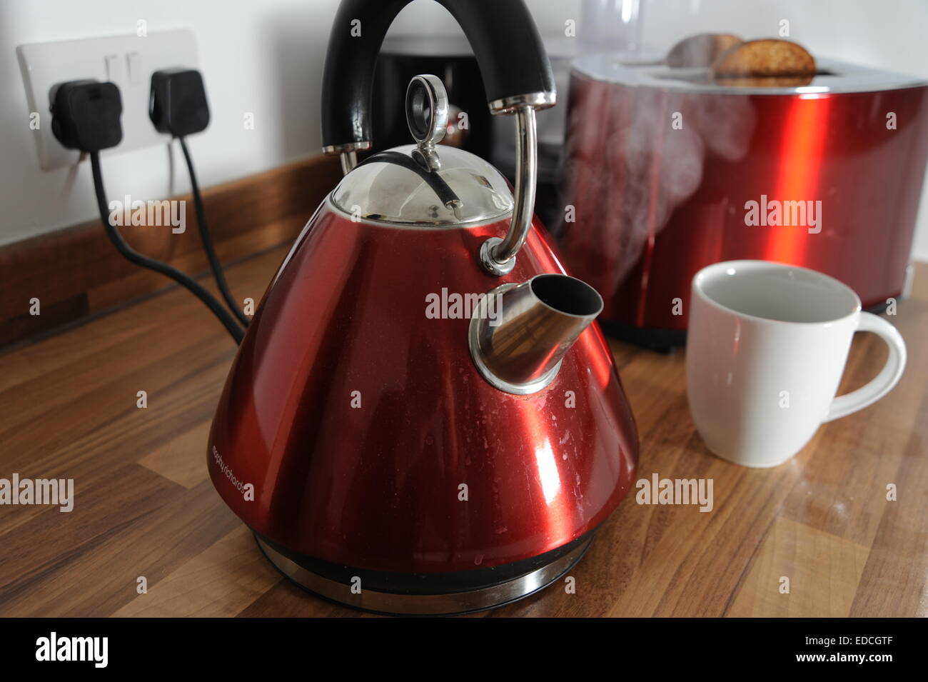 Kettle boiling with steam and toaster cooking toast behind in kitchen