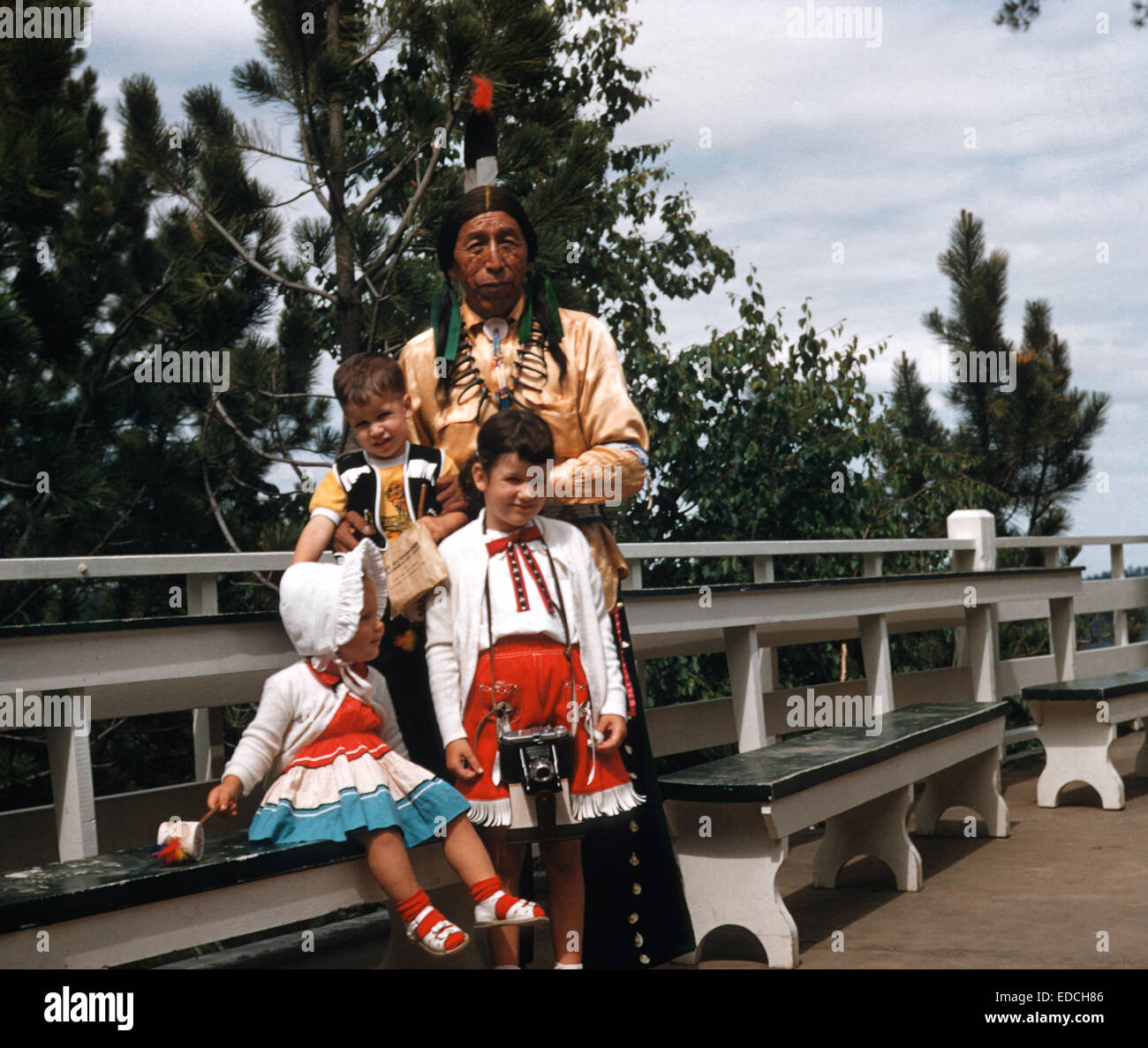 Vintage 1950's Image of Colorfully Dressed Children with Native American Man, Mount Rushmore, South Dakota, USA Stock Photo
