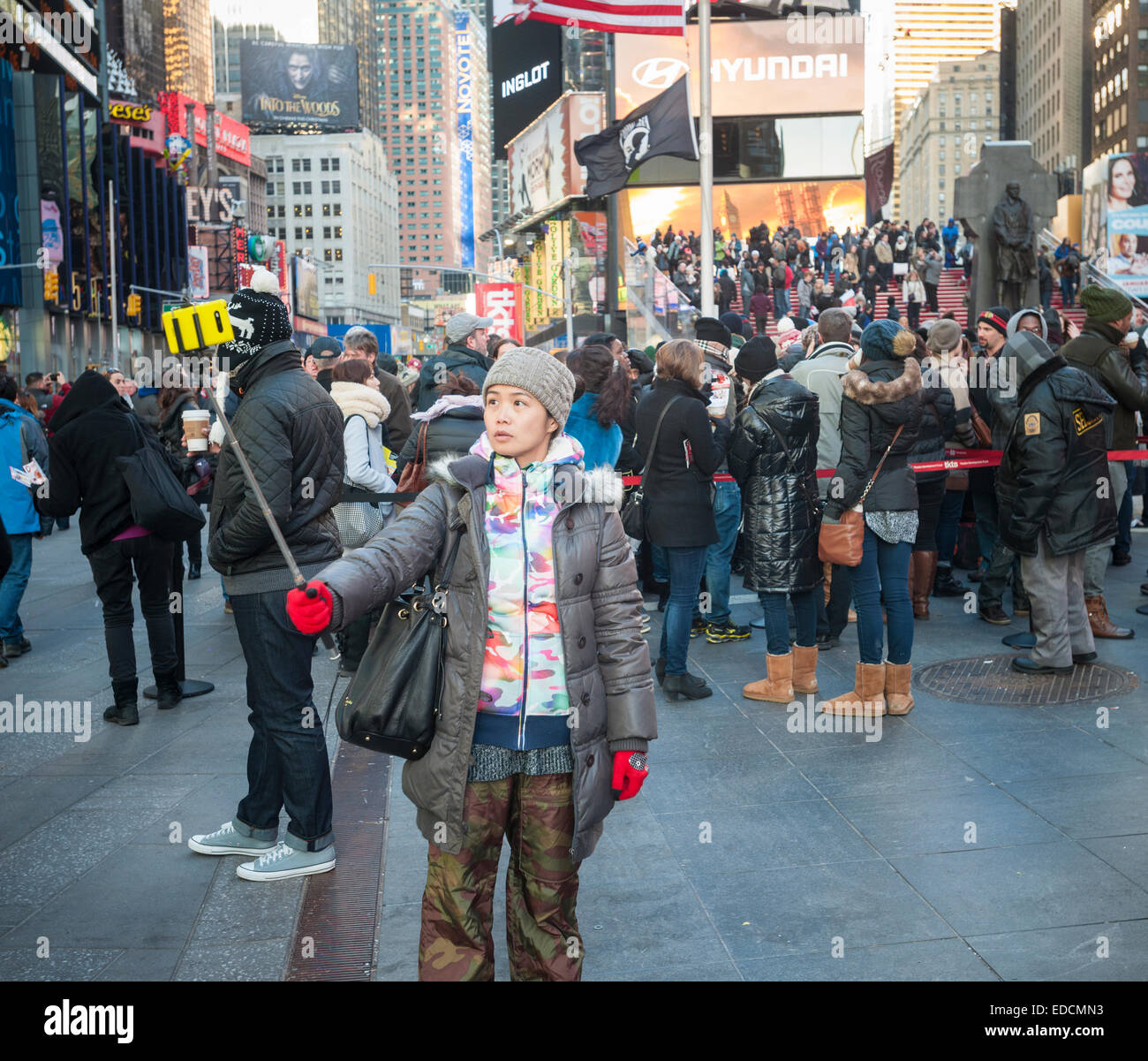 Tourists in Times Square in New York use their selfie sticks to take