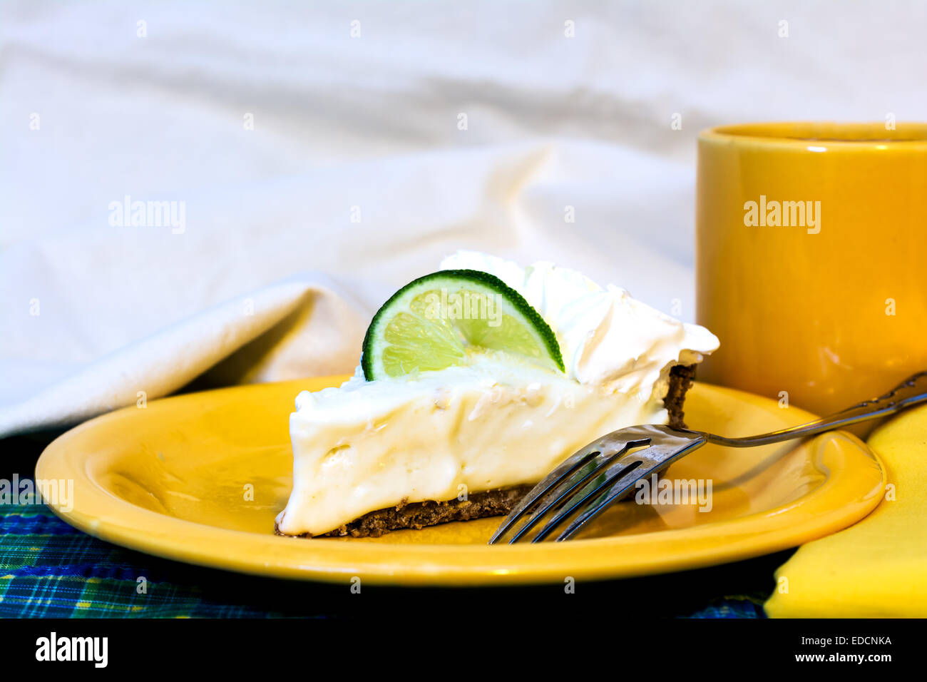Slice of key lime pie with coffee closeup on plate with fork and napkin. Stock Photo