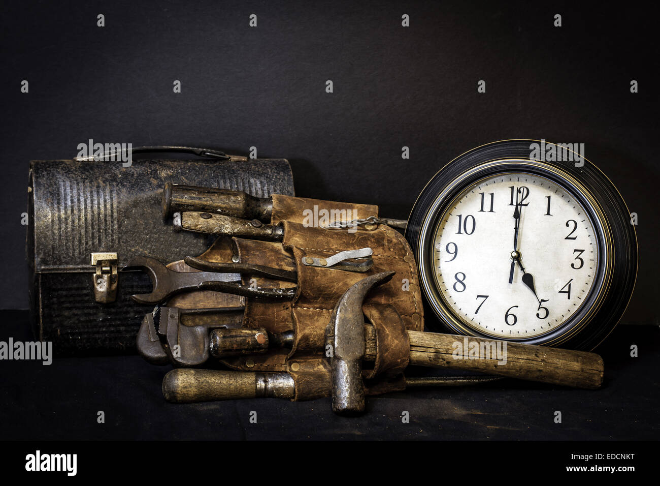 Quittin time.  Vintage tool belt and lunch box with tools and clock showing 5 o'clock. Stock Photo