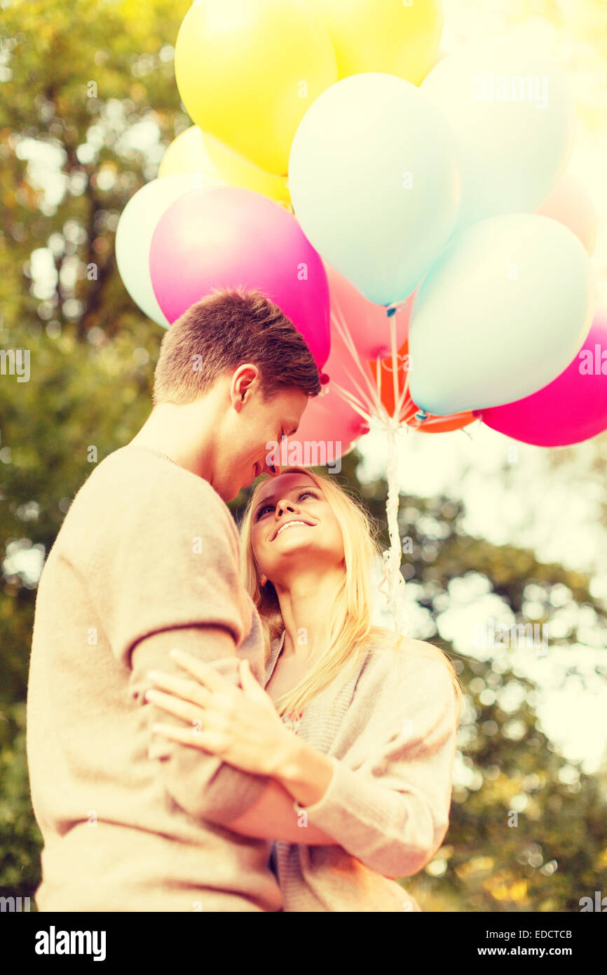 smiling couple with colorful balloons in park Stock Photo