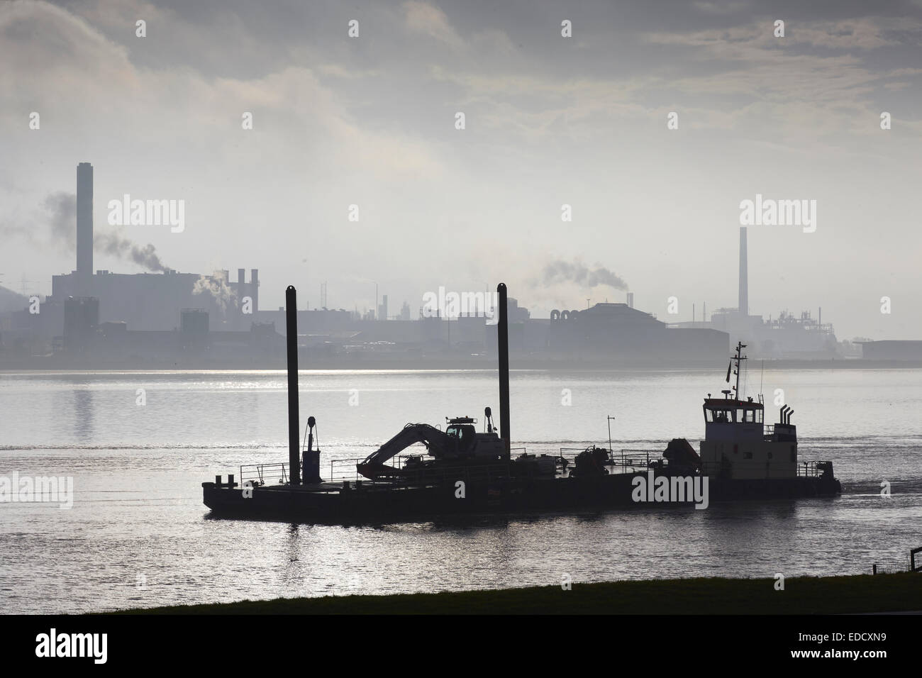 A skimmer boat on the River Mersey passing Runcorn ICI in the mist Stock Photo