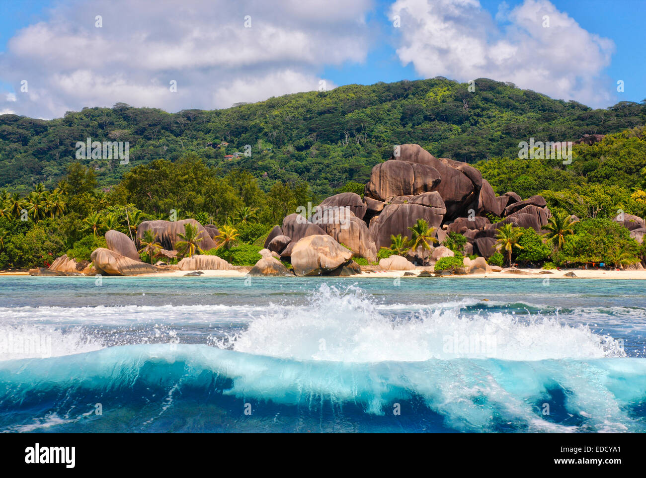 Big waves in front of granite rocks and a hill on island la Digue, Seychelles. Beach - Anse source d' Argent. Stock Photo