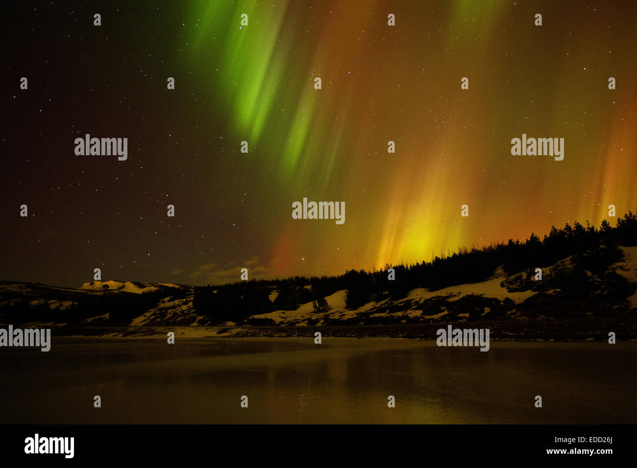 The northern lights, aurora borealis over a mountainous frozen lake ...