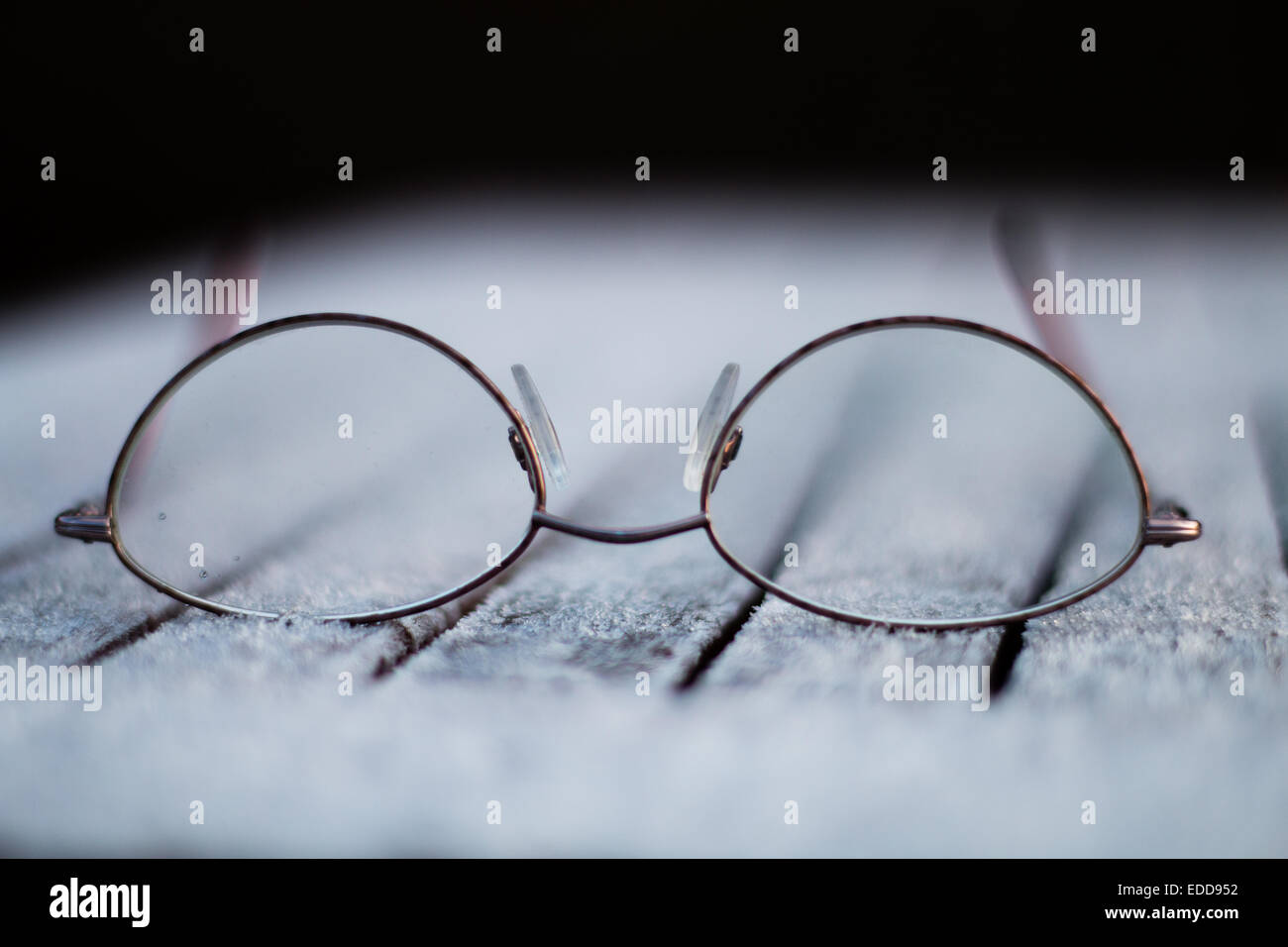 A pair of spectacles on a frost covered table. Stock Photo