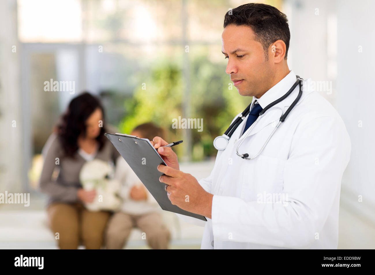 handsome pediatric doctor writing on clipboard Stock Photo