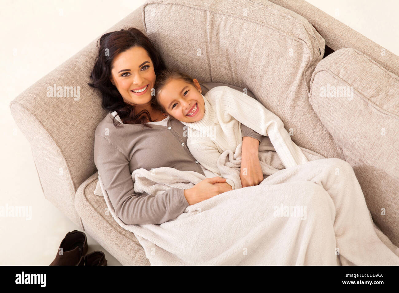 beautiful young girl and her cute mother lying on the couch Stock Photo