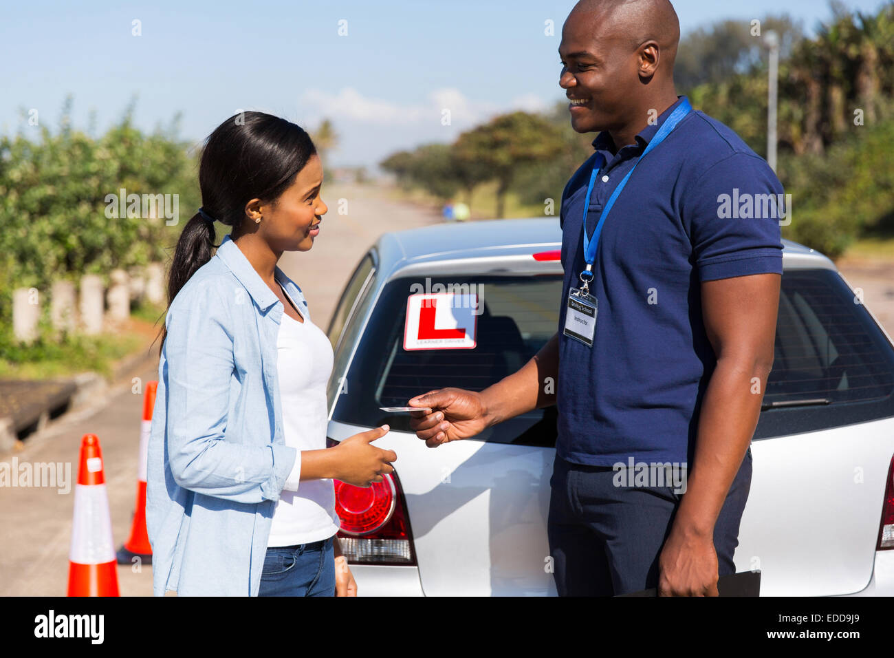friendly African driving instructor handing driving license to student driver Stock Photo