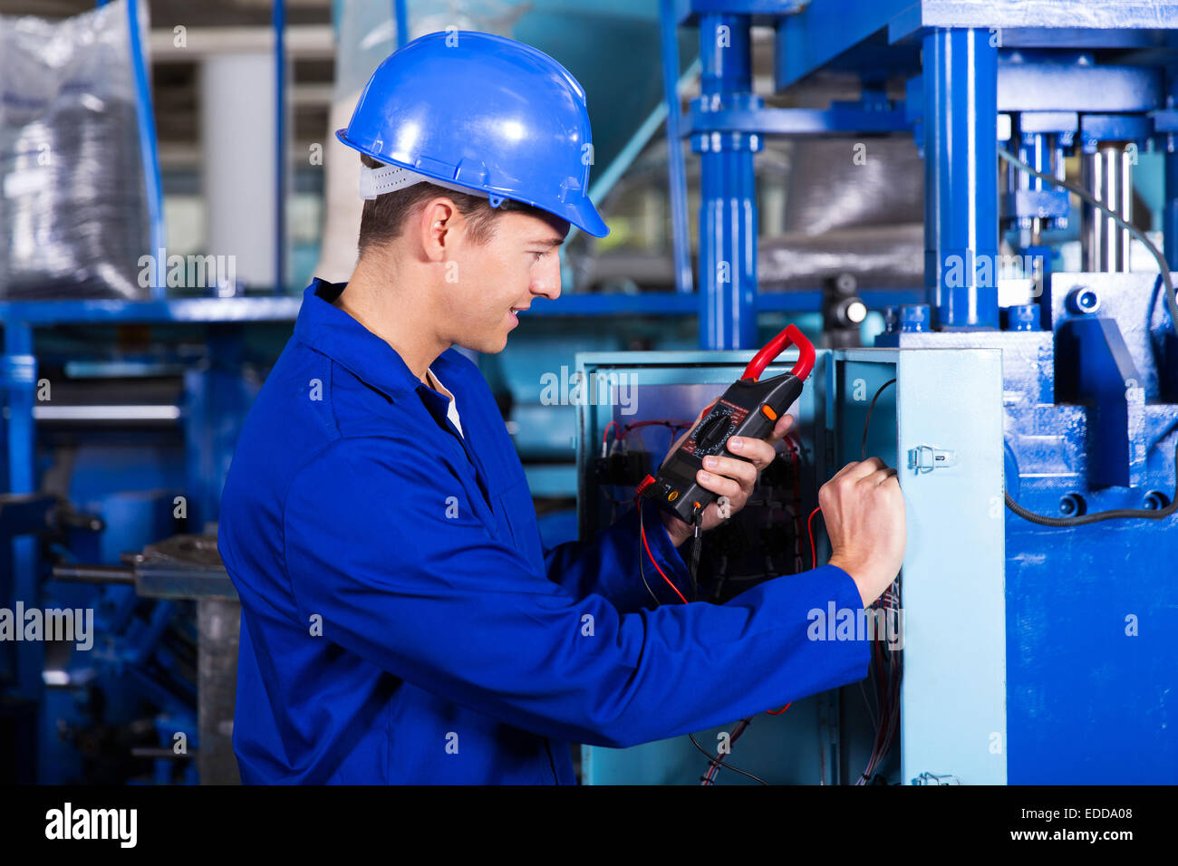 industrial technician examining control box with digital insulation tester Stock Photo