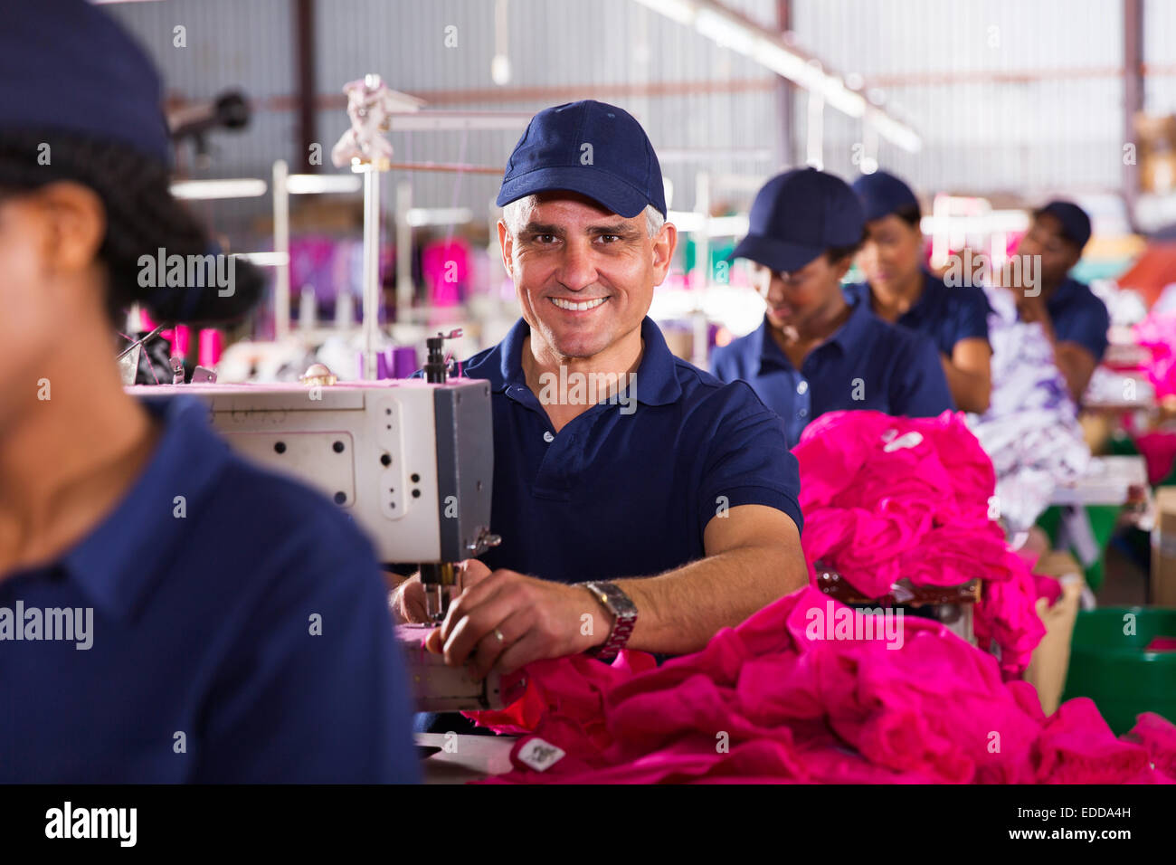 middle aged male textile worker sewing in clothing factory Stock Photo