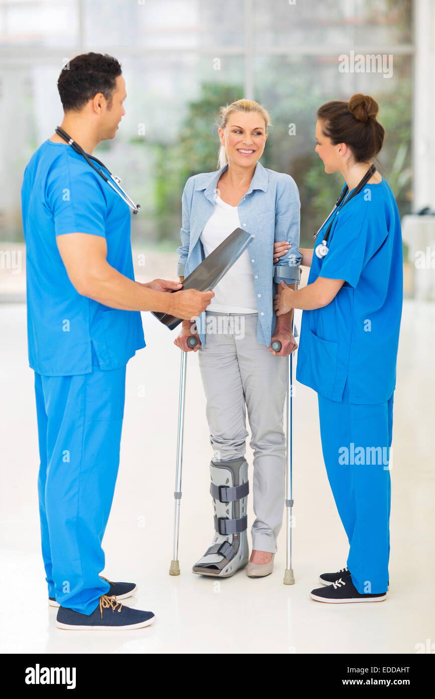 friendly healthcare workers with injured woman on crutches in hospital Stock Photo