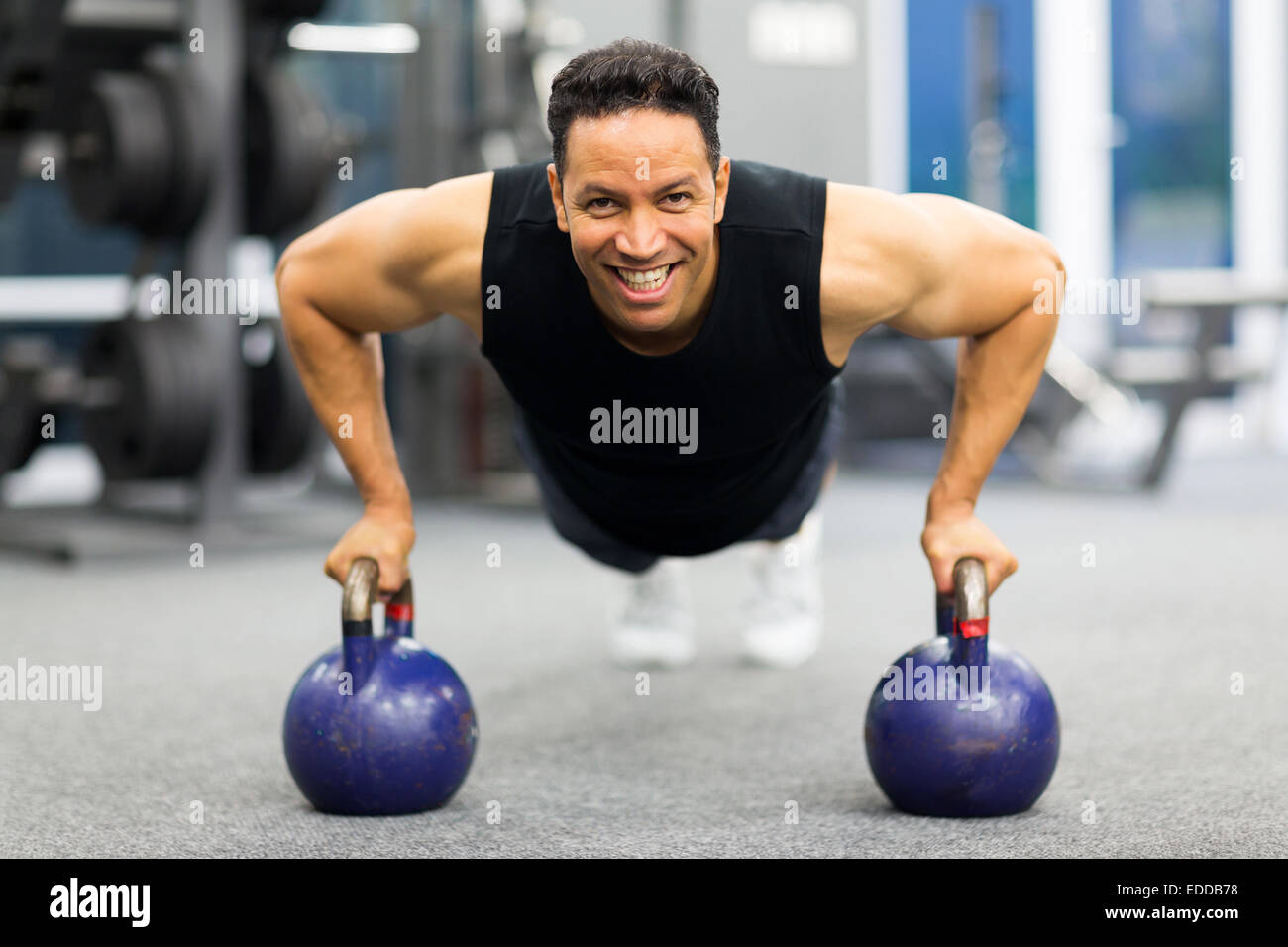 healthy man doing pushup exercise with kettle bell in gym Stock Photo
