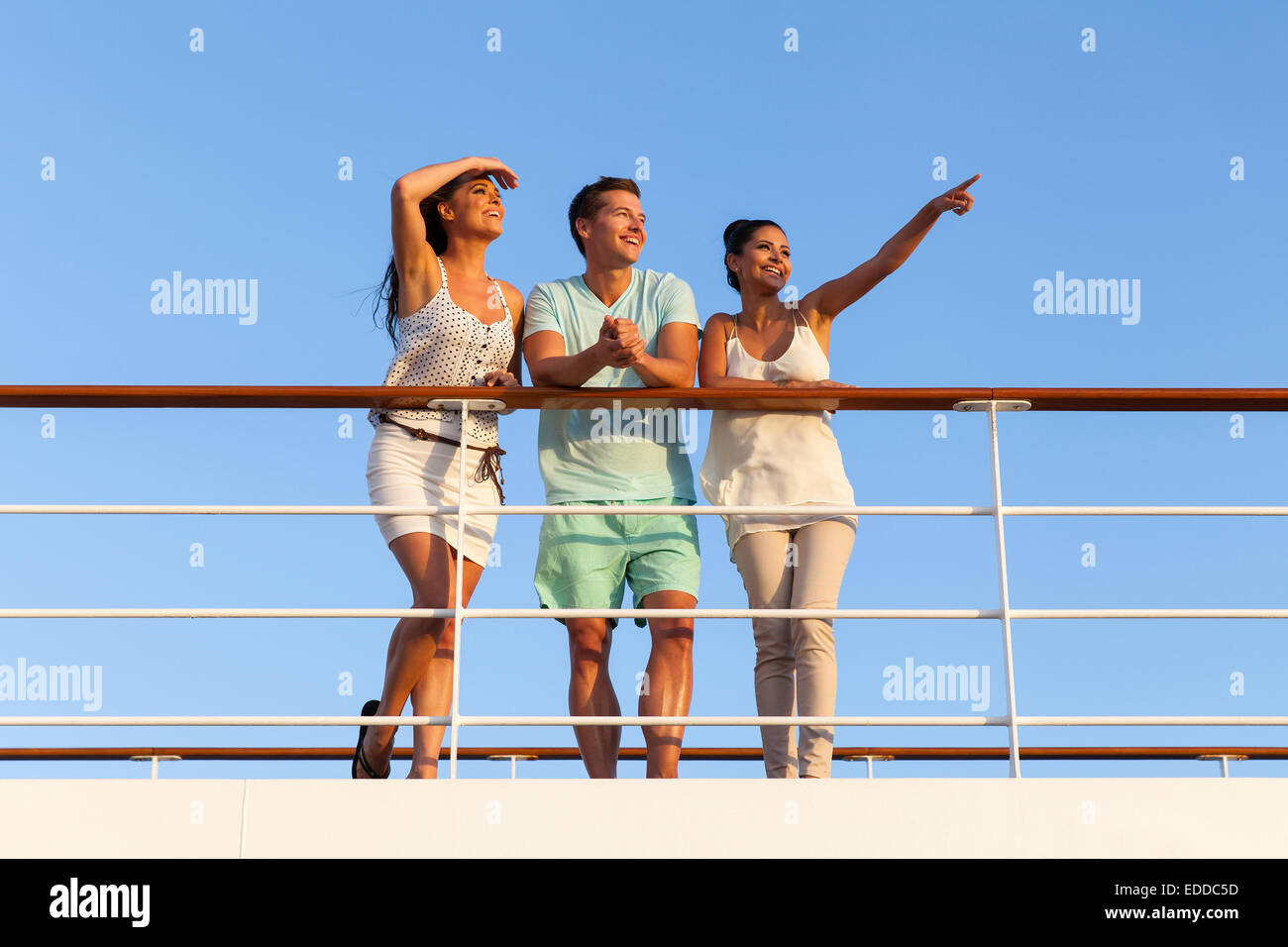 group of cheerful friends enjoying sunset on cruise Stock Photo