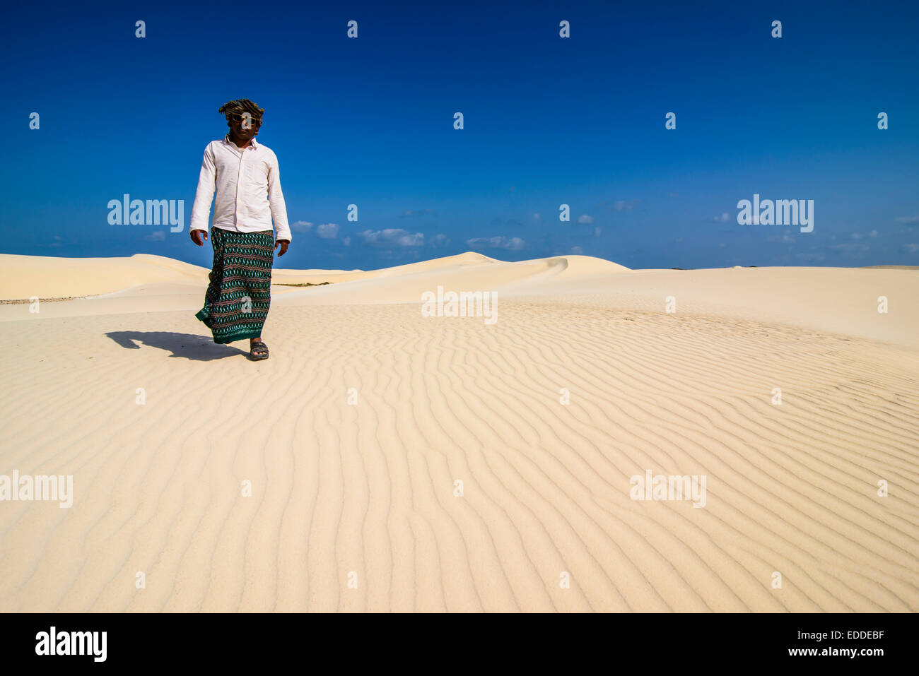 Local man walking through the sand dunes at the south coast of the island of Socotra, Yemen Stock Photo