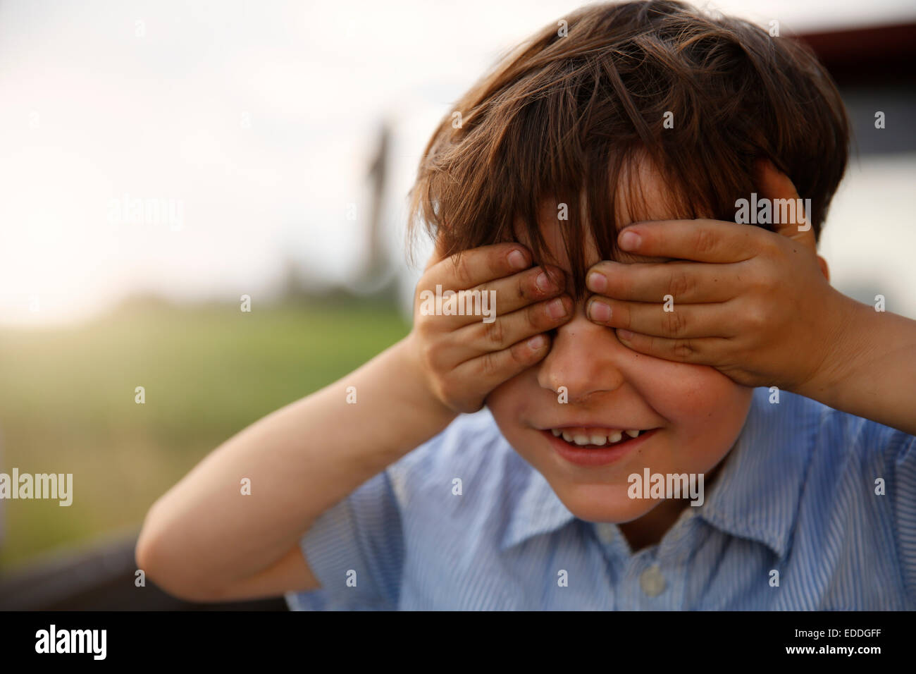 Portrait of smiling little boy covering eyes with his hands Stock Photo ...