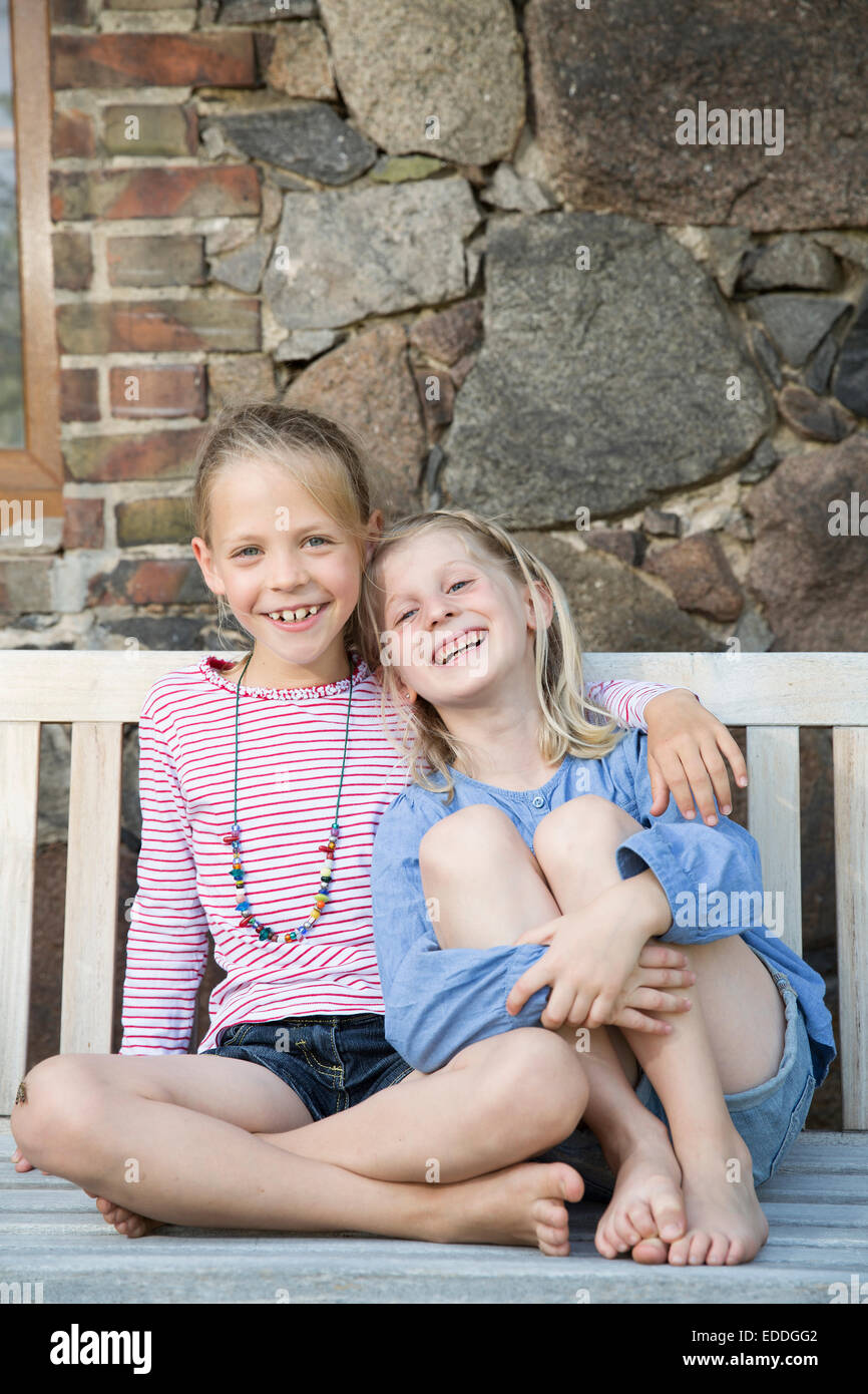 Portrait of two smiling girls sitting on a bench Stock Photo - Alamy