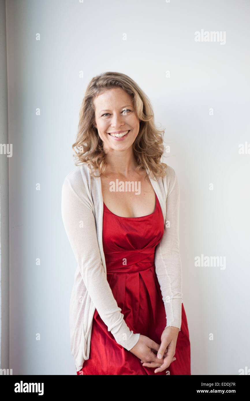 Portrait of smiling mature woman wearing red dress Stock Photo - Alamy