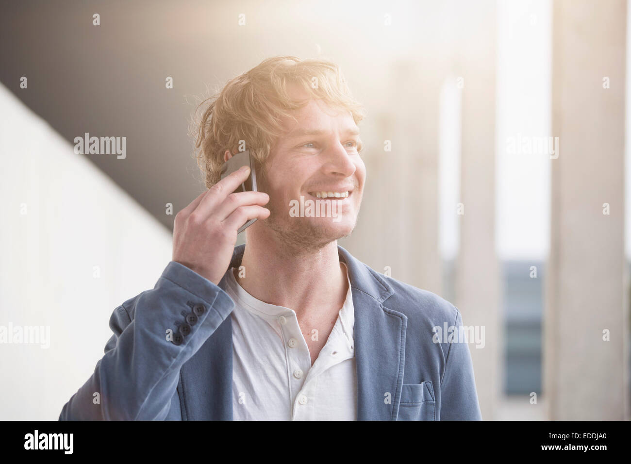 Portrait of smiling man telephoning with smartphone at backlight Stock Photo
